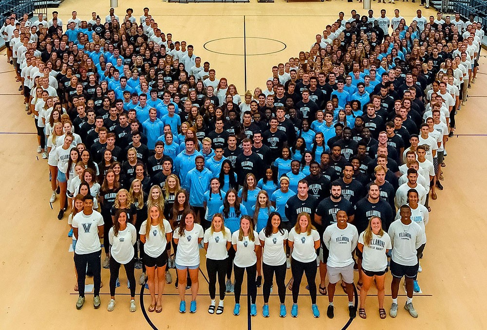 Villanova student-athletes for a human letter 'V' on the floor of the basketball court