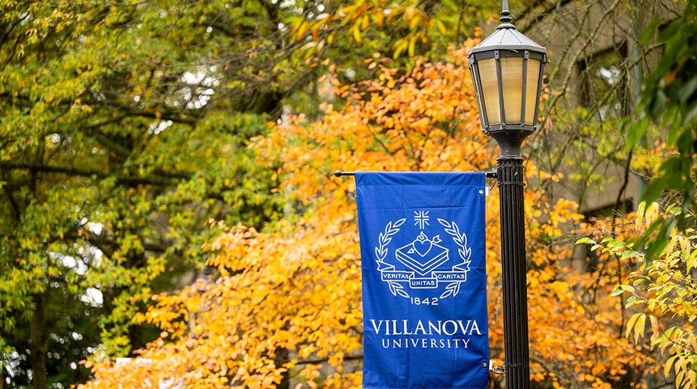 Villanova lightpost banner in front of fall leaves