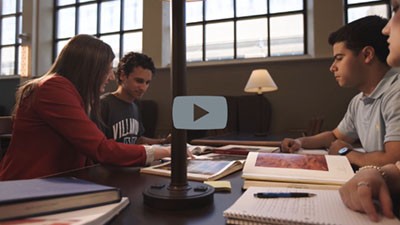 Whitney Martinko, PhD, sitting with three students at a table in the library.