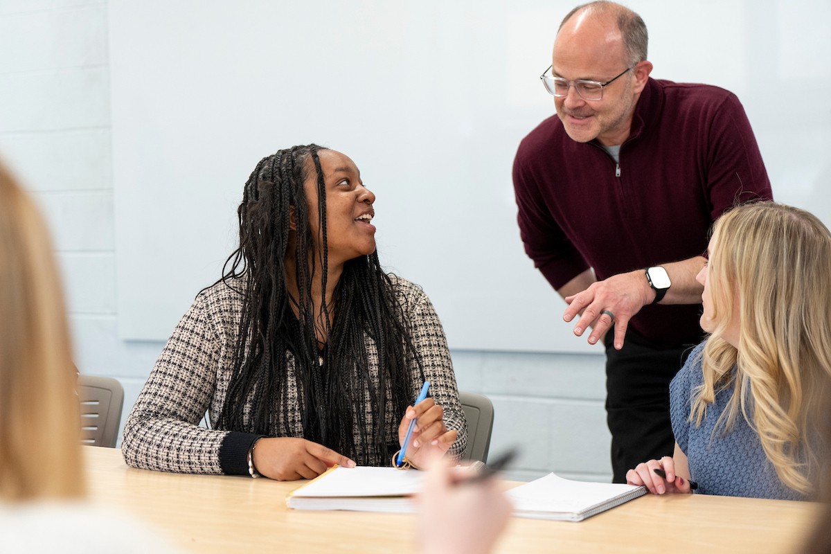 A Villanova faculty members talks to two students during a class.