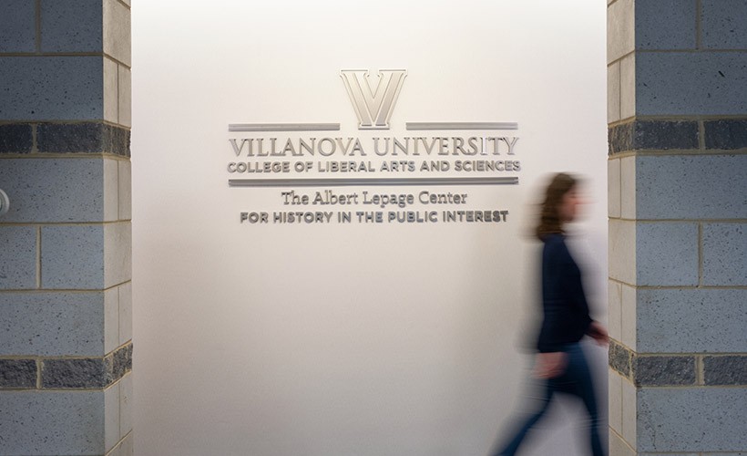 A person walks by the Lepage Center sign outside the office.