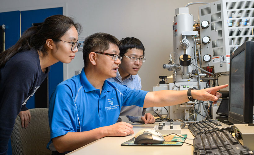 Professor and students viewing computer screen