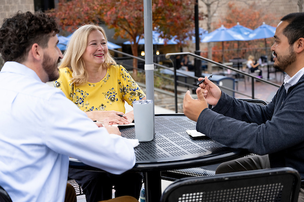 three people sitting at a table outside of Vasey Hall