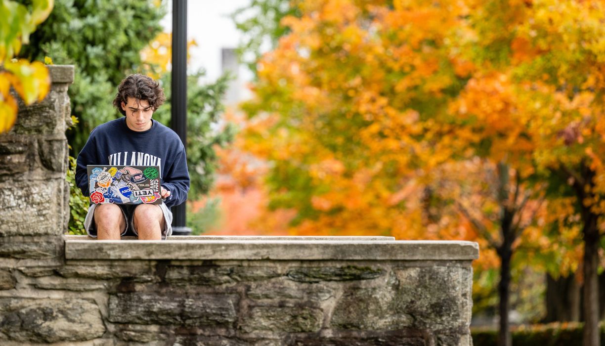 Student at laptop on campus in the Fall.