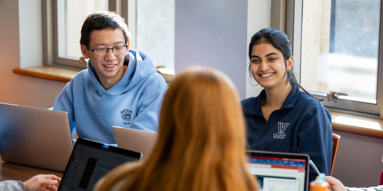 Students talking while working on their laptops.